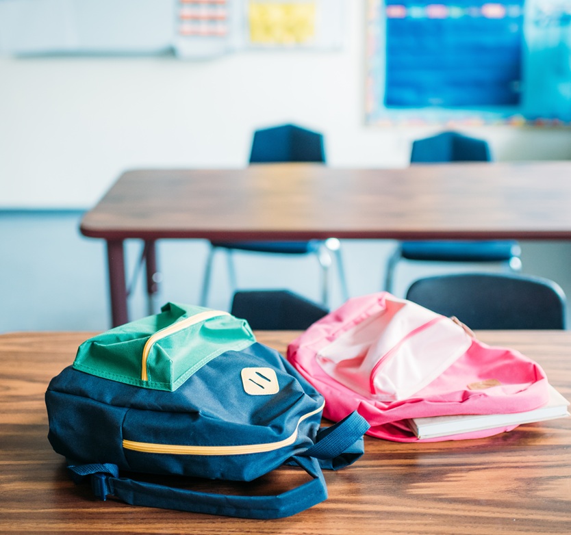 backpacks laying on desk in school classroom content-image